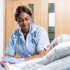 Student nurse tends to an elderly patient in bed